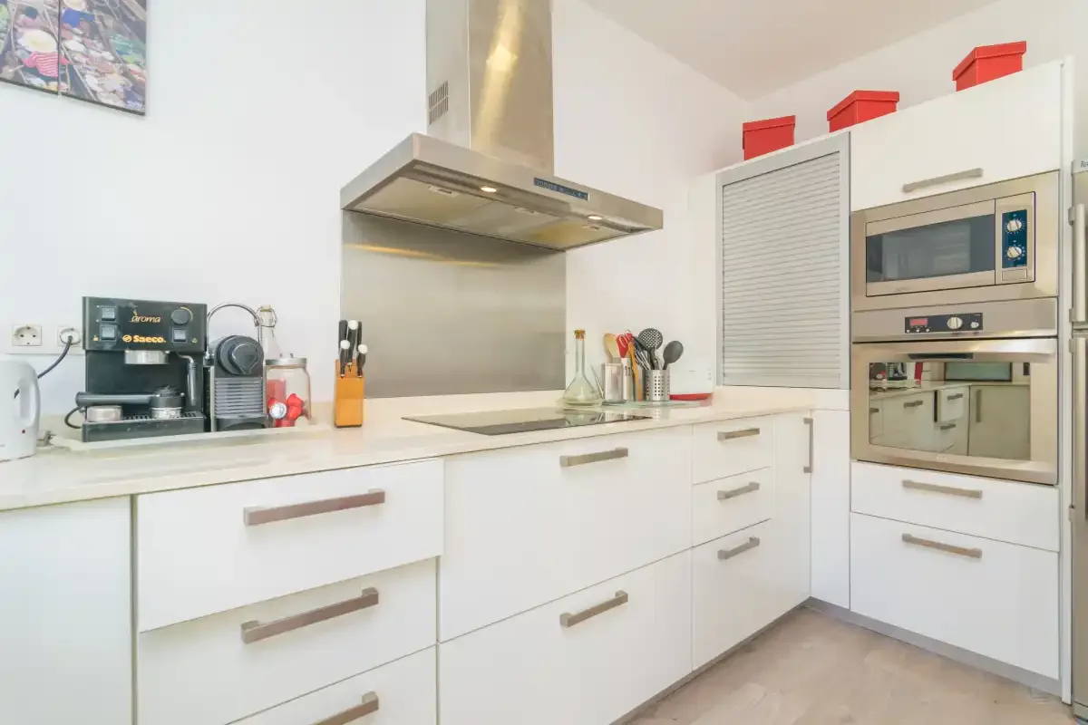 A bright kitchen with white cabinets, a countertop, and built-in appliances.