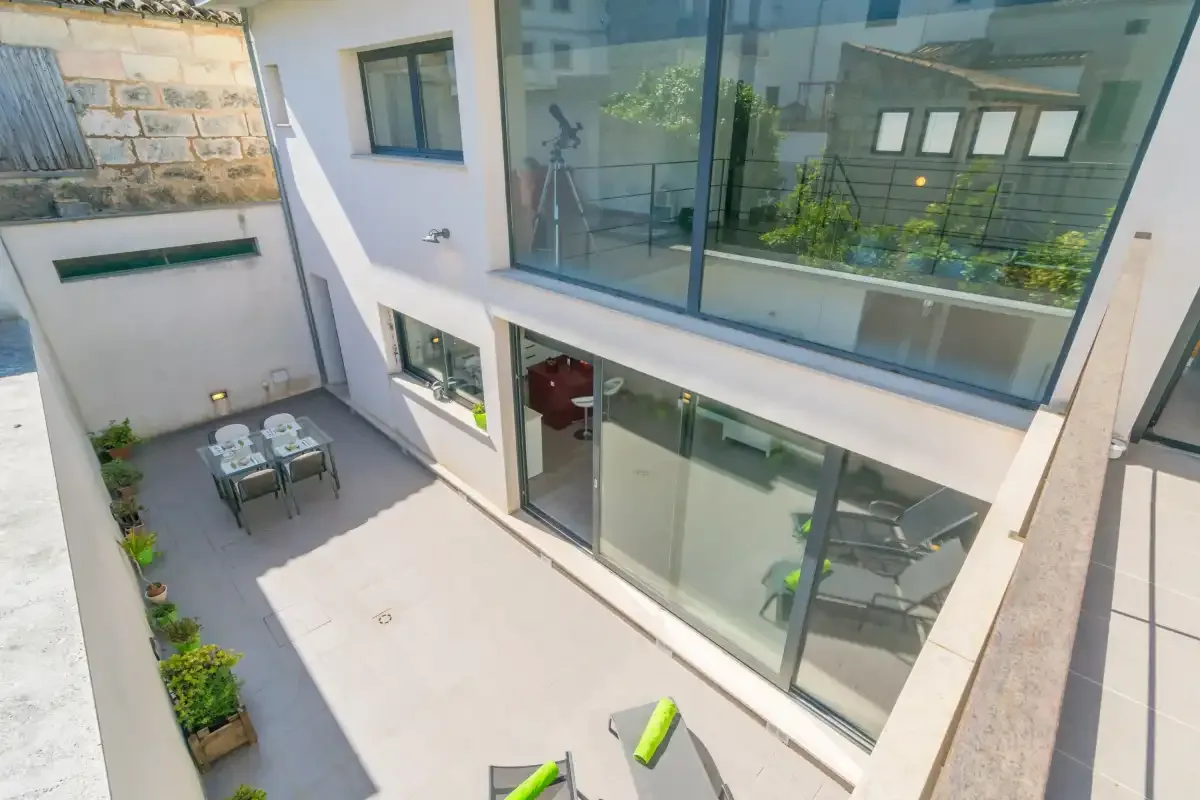 A modern courtyard with a small outdoor dining area beside large glass windows.