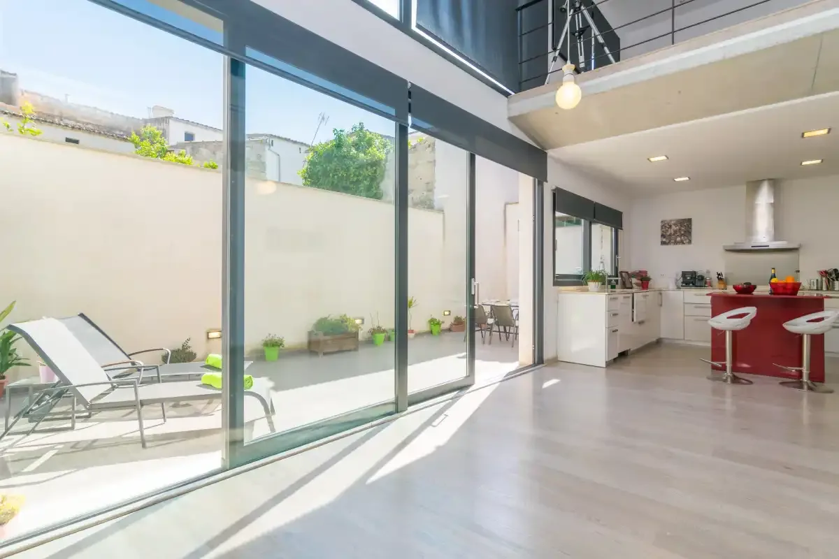 A bright open-plan kitchen and dining area opens onto a sunlit patio.