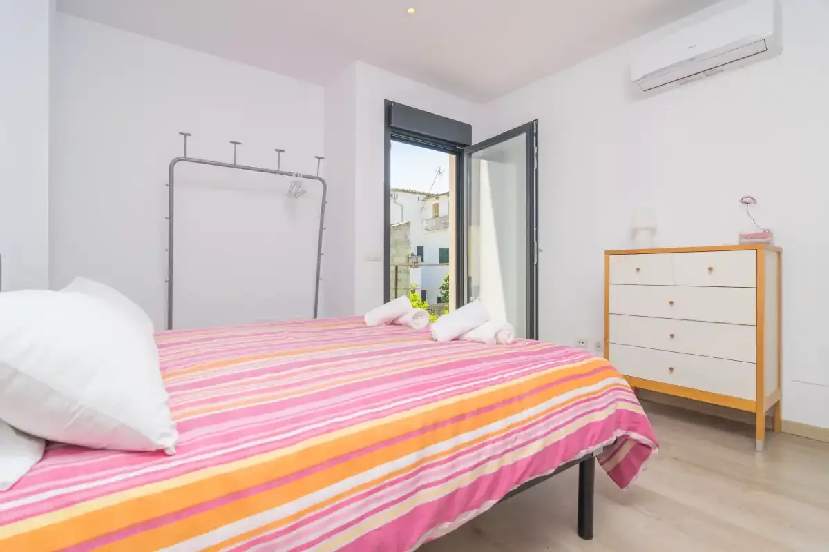 A bedroom with a colorful striped bedspread and an open balcony door.