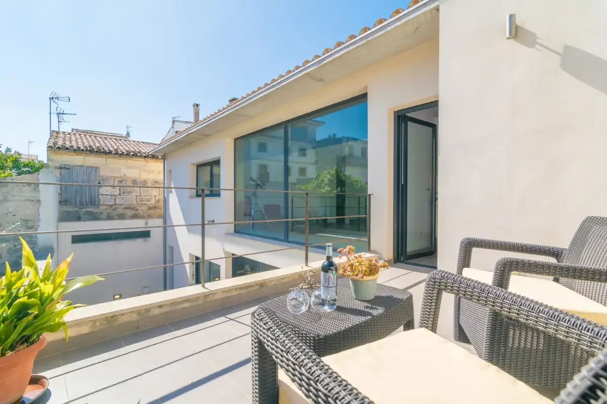 A sunny terrace with outdoor seating and large glass doors.