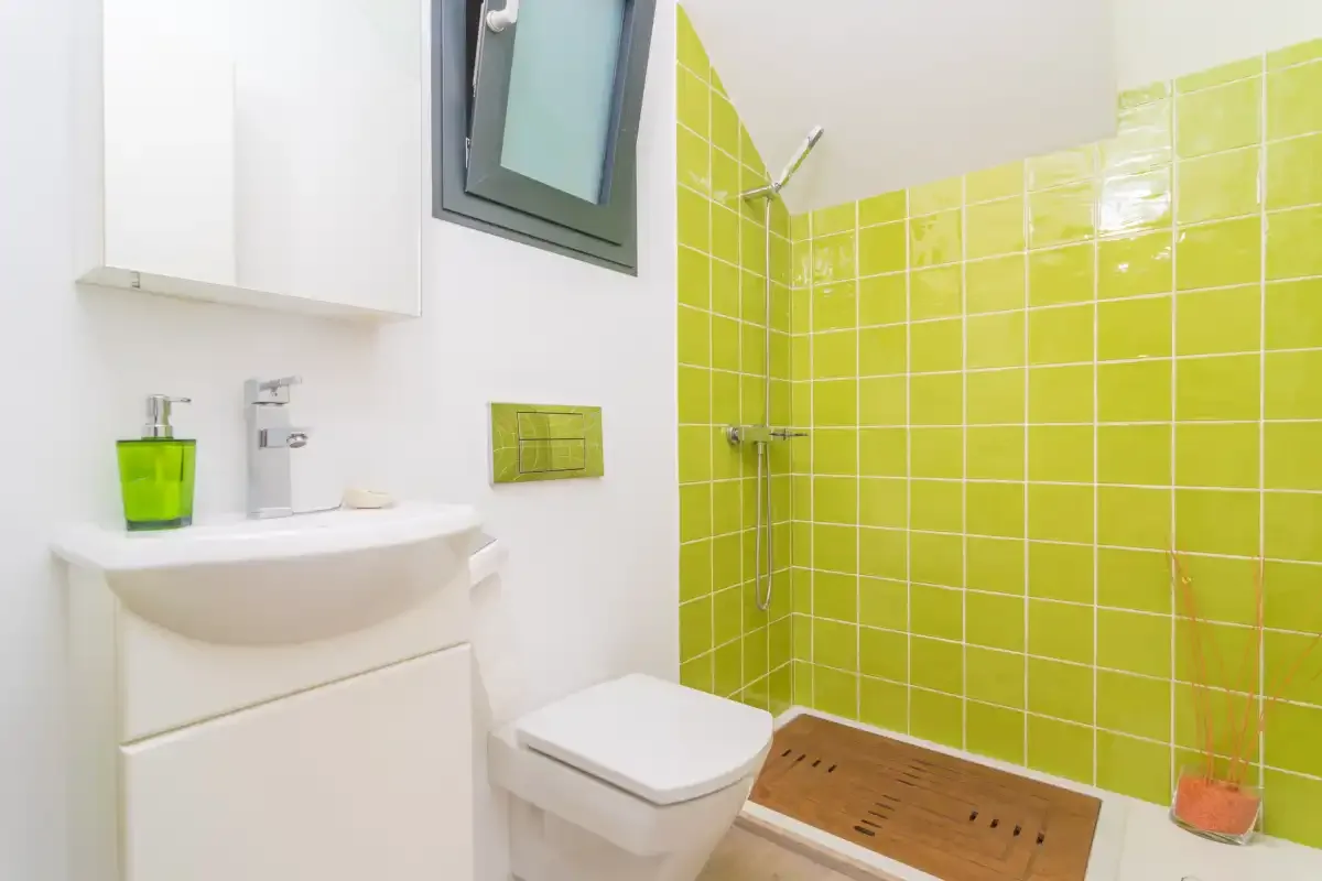 A bathroom with a sink, toilet, and tiled shower area.