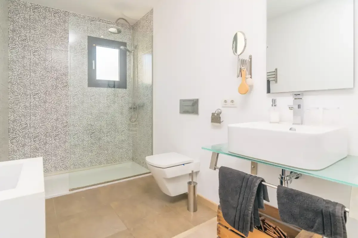 A bright bathroom with a glass shower, toilet, and sink.