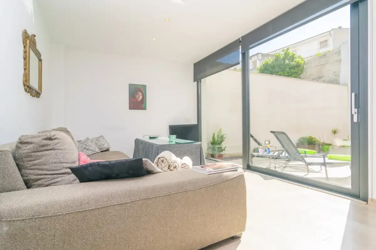 A bright living room opens onto a patio through large glass doors.