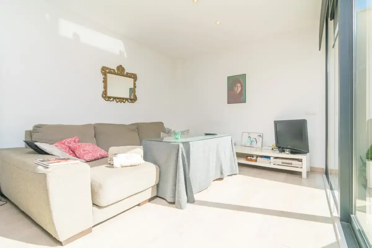 A bright living room with seating, a table, and a television.