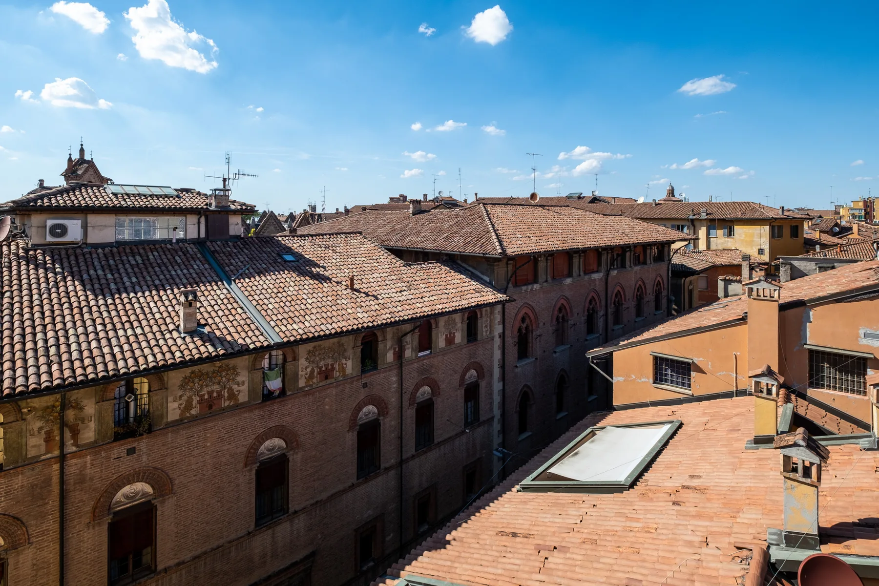 Un paisaje urbano de edificios históricos muy juntos con tejados de terracota bajo un cielo azul despejado.