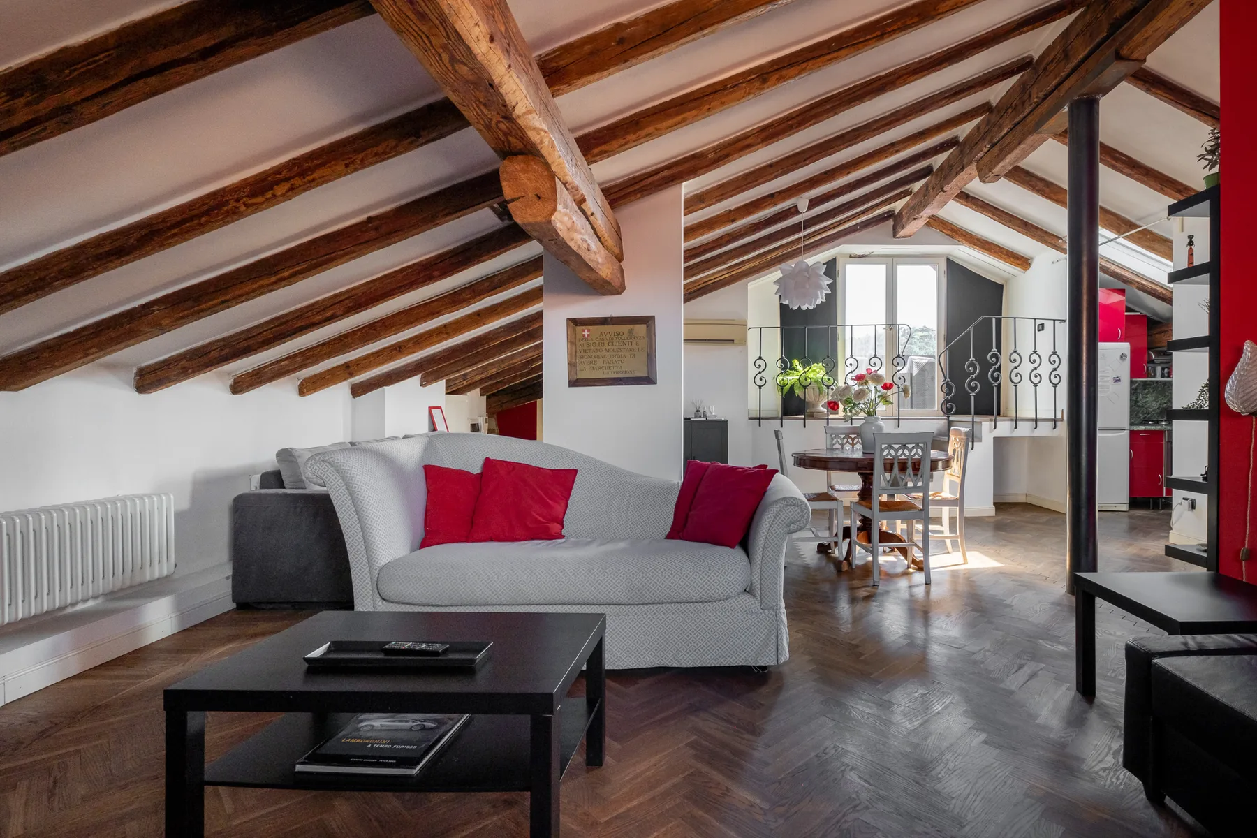Una sala de estar con asientos y un comedor bajo vigas de madera a la vista.