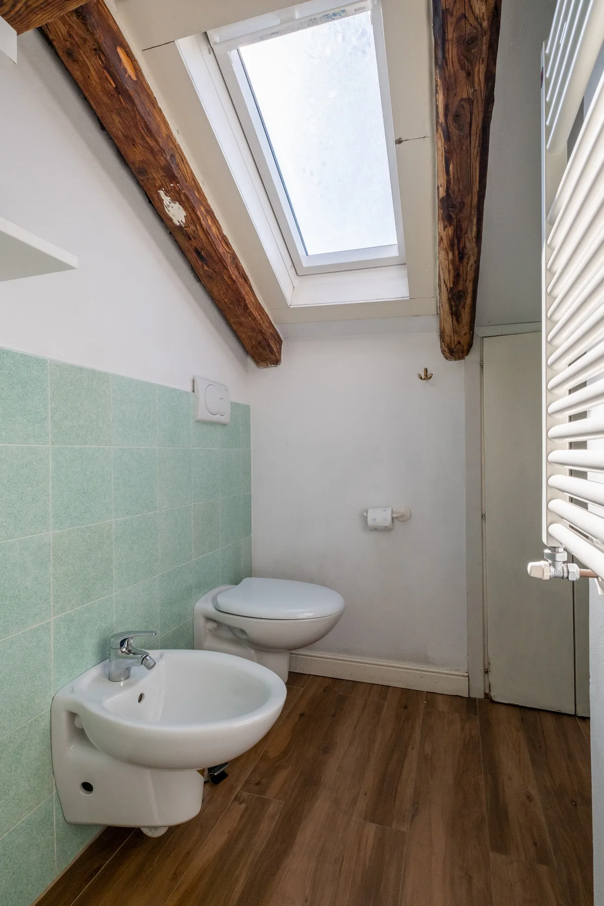 Un baño con lavabo e inodoro bajo una claraboya.