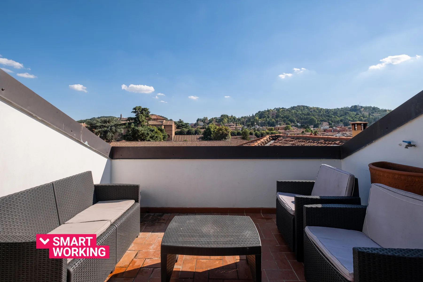 Una terraza en la azotea con asientos al aire libre y vistas a las colinas cercanas.