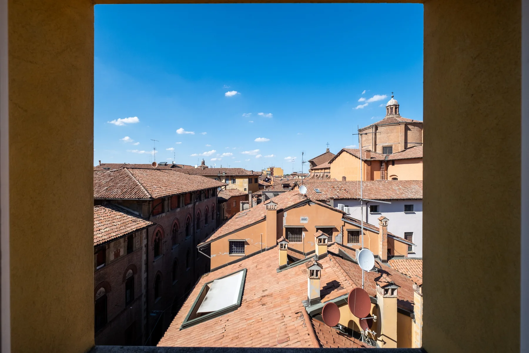 Vista de tejados de terracota y edificios históricos bajo un cielo azul despejado.