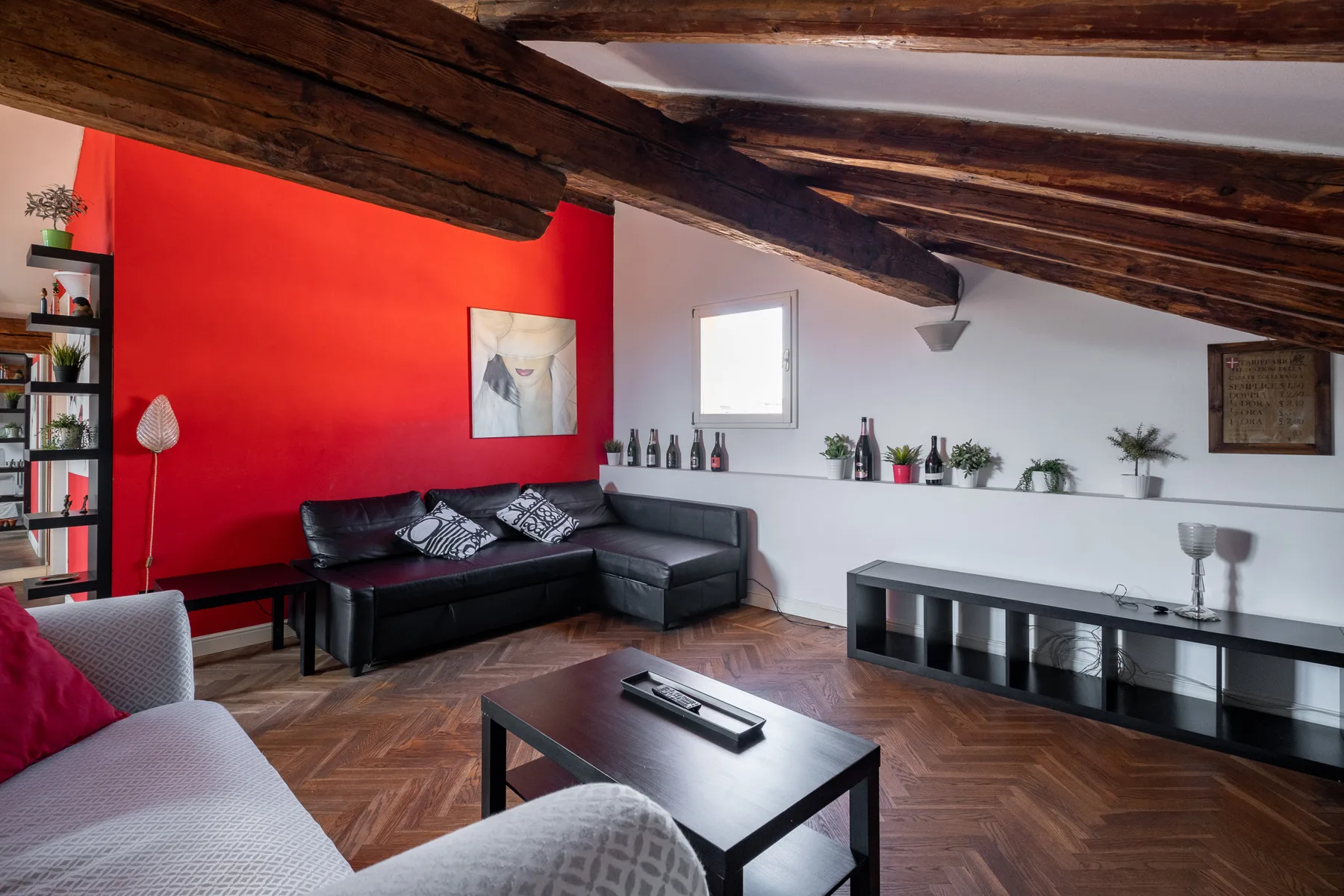 Una sala de estar con asientos oscuros, una mesa de centro y una pared roja.