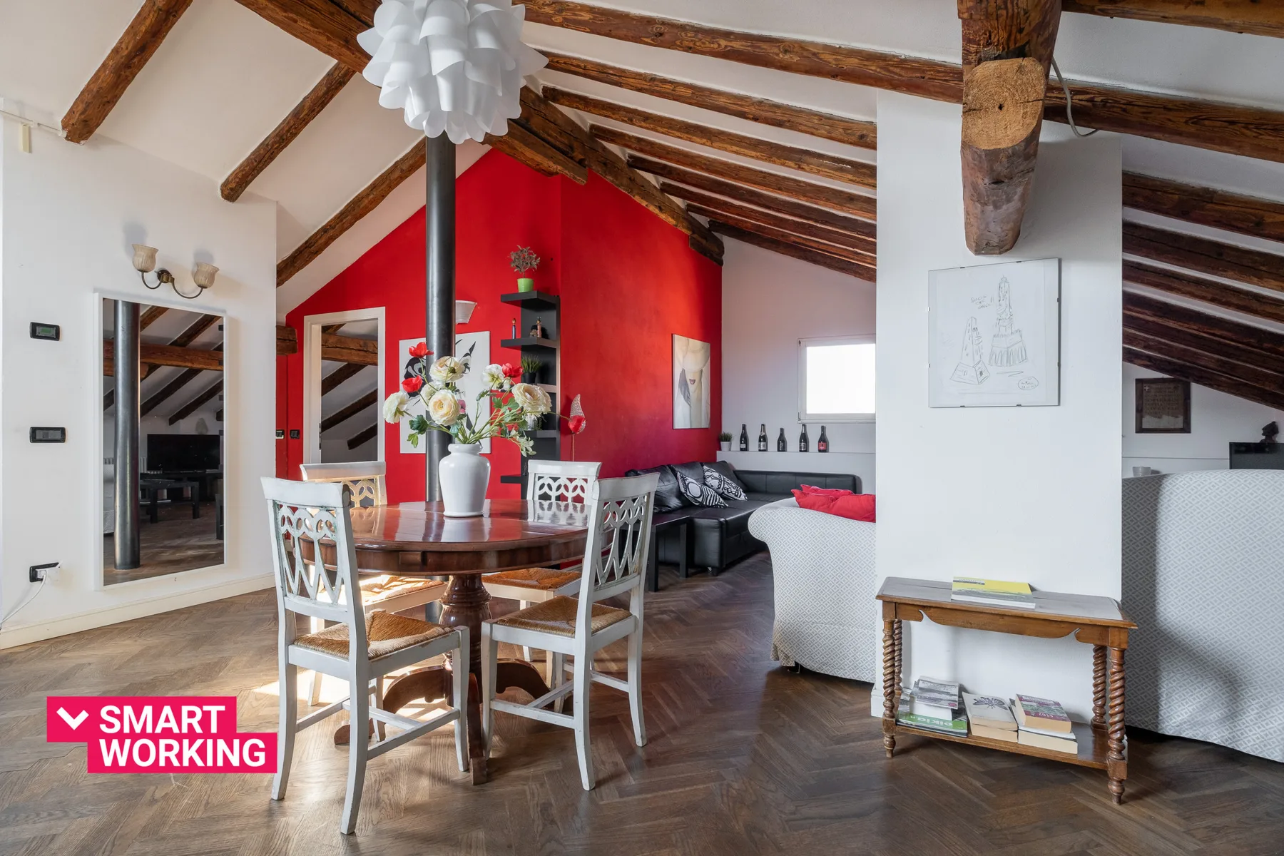 Una zona abierta de estar y comedor con una mesa de madera bajo vigas vistas.