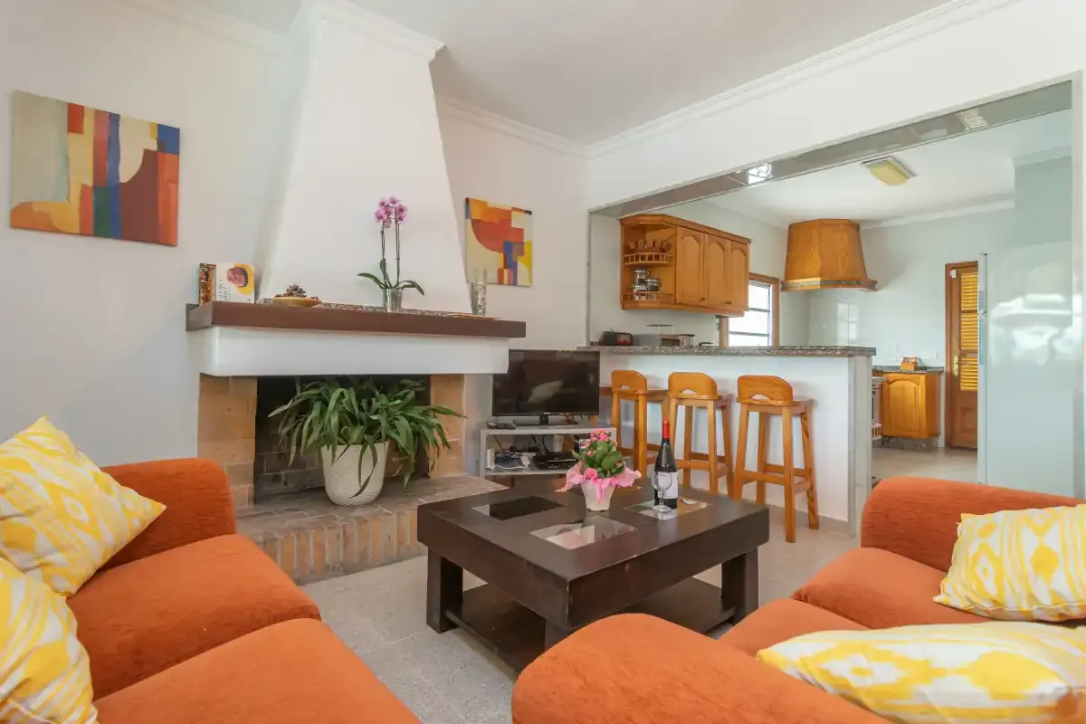 Living room with orange seating, a fireplace, and an open kitchen.