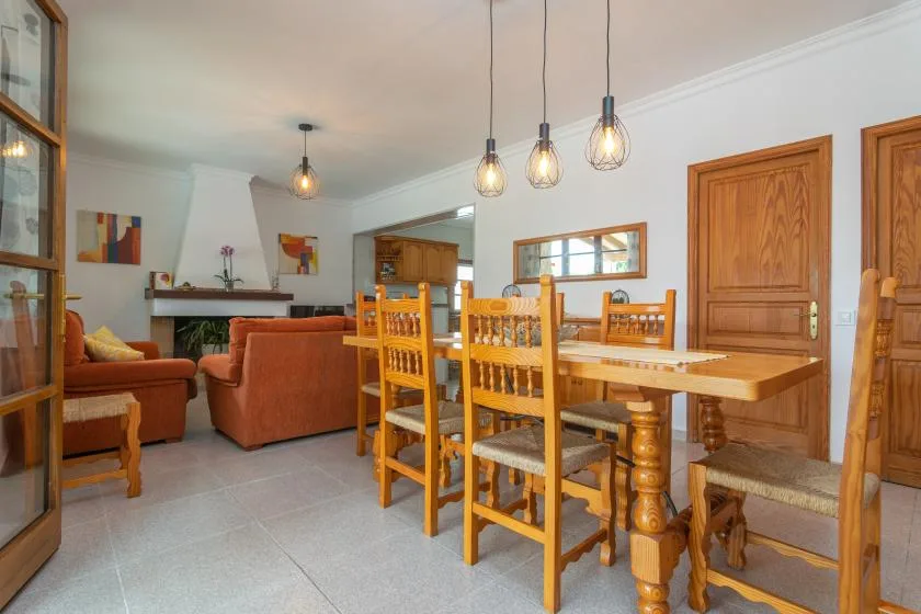 A dining area with a long wooden table and chairs beside a living area.