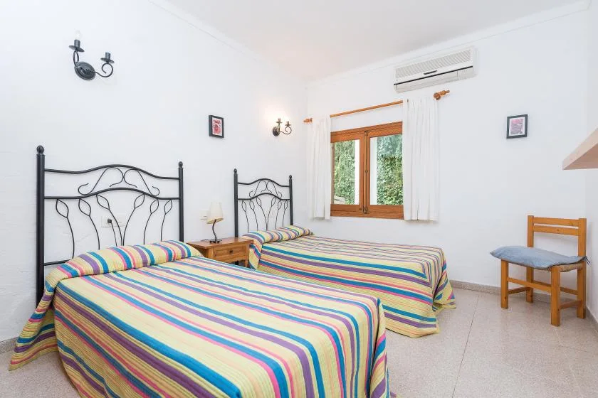 A bright bedroom with two beds covered in colorful striped bedding.