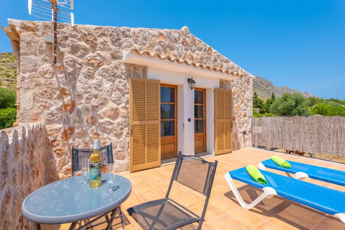 A sunny outdoor patio with a small table, seating, and a blue sun lounger.