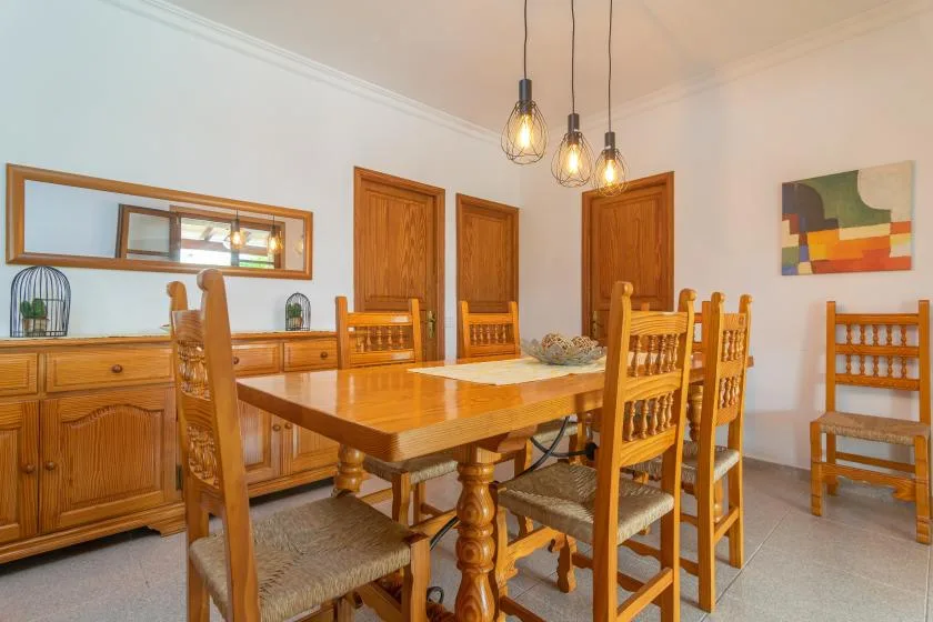 A dining room with a wooden table and chairs beneath pendant lights.