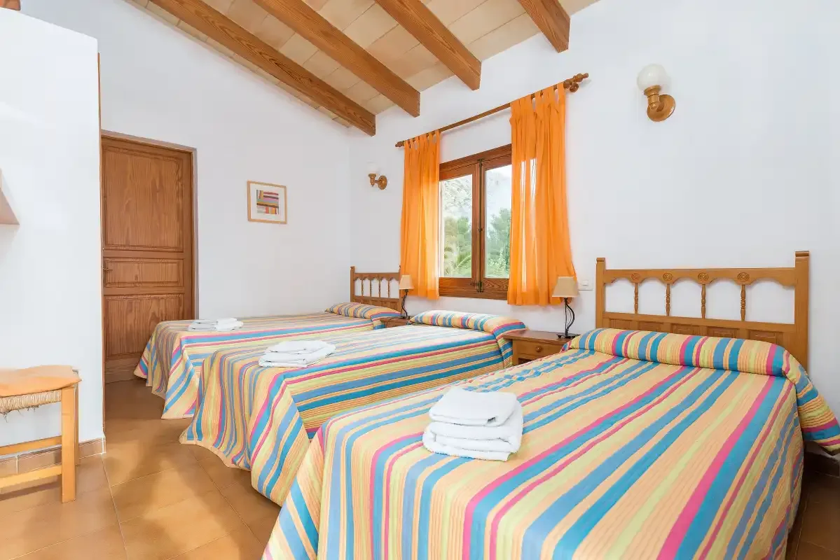 A bedroom with two beds covered in colorful striped bedding.