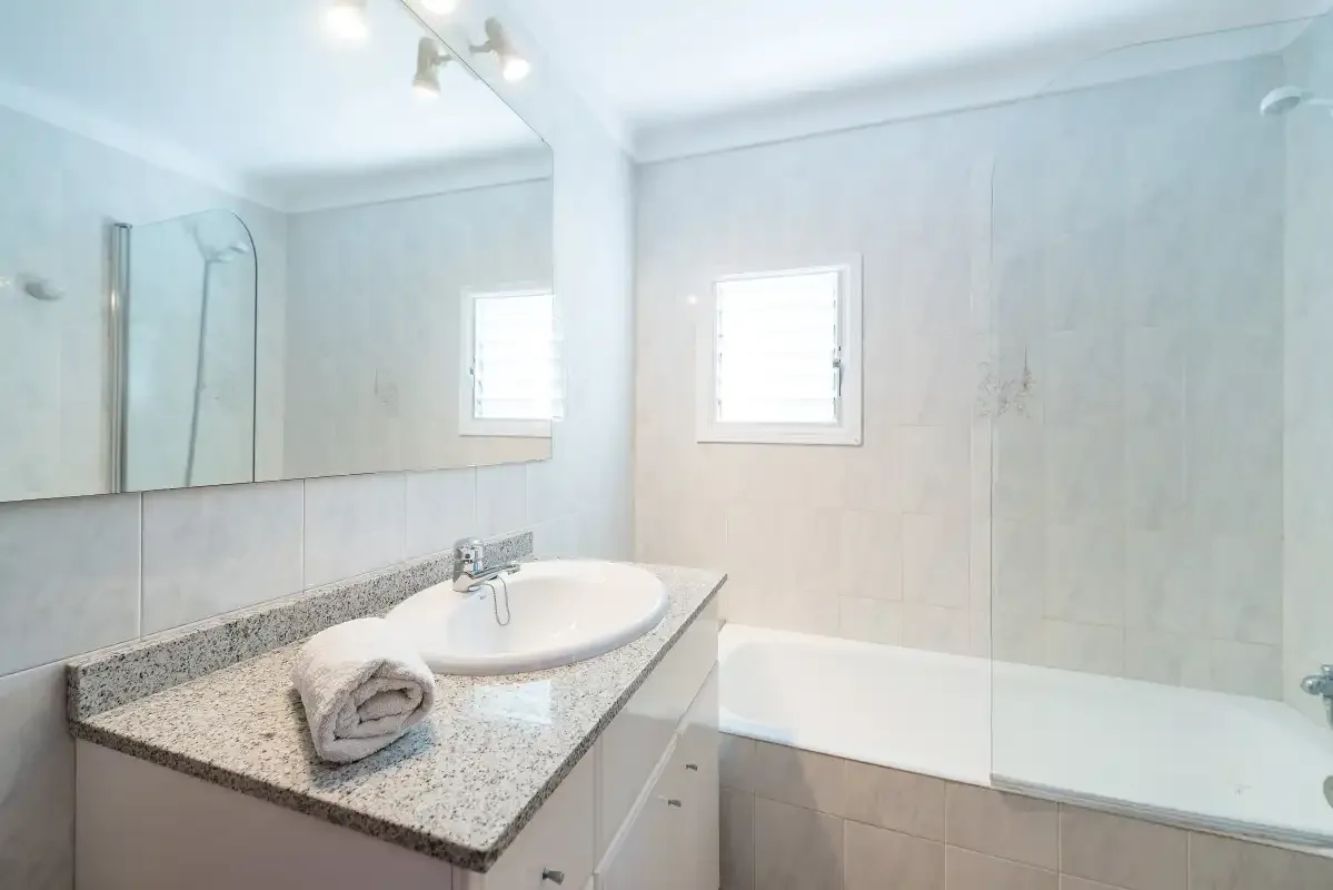 A bright bathroom with a wide sink counter and a bathtub.