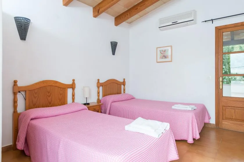 A bedroom with two beds covered in pink bedspreads.