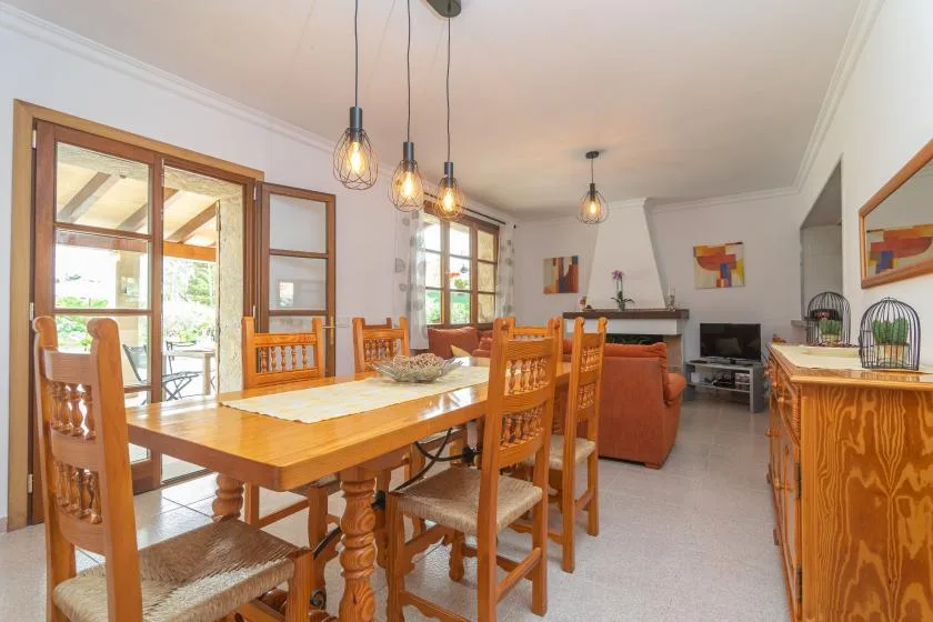 A dining area with a wooden table and seating, open to a living area.
