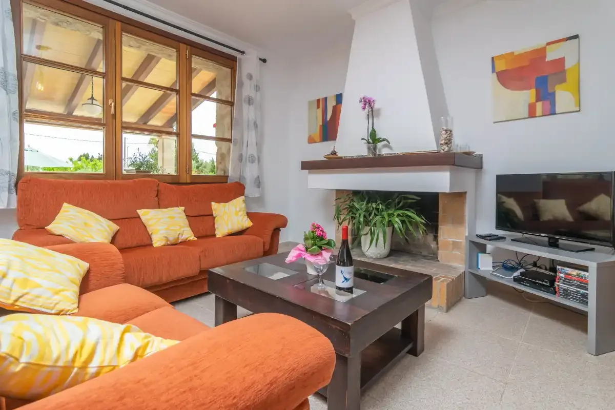A living room with orange seating, a coffee table, and a fireplace.