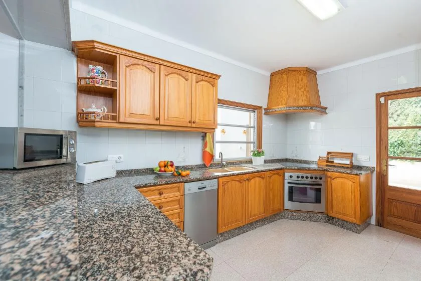 A bright kitchen with wooden cabinets and a speckled countertop.