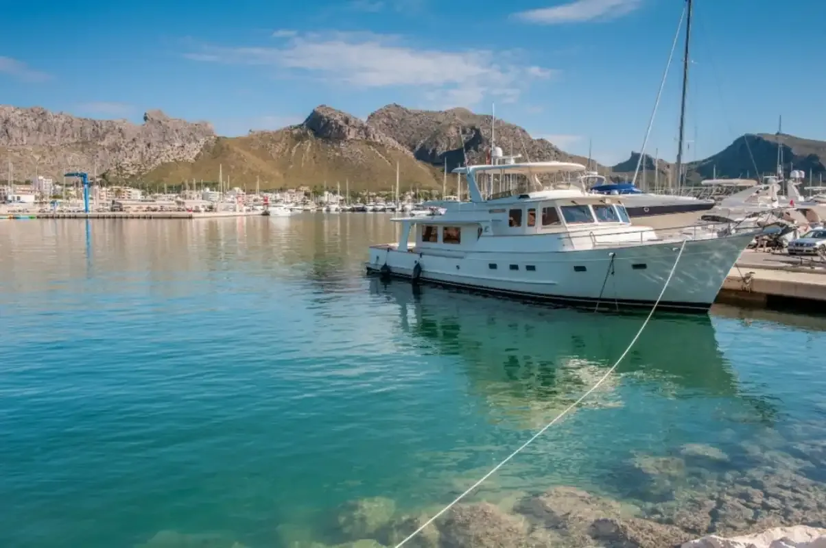 A motorboat floats in a marina with mountains visible in the background.