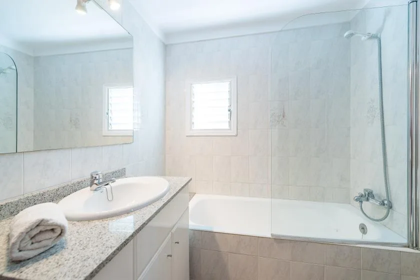 A bright bathroom with a bathtub and a sink beneath a window.