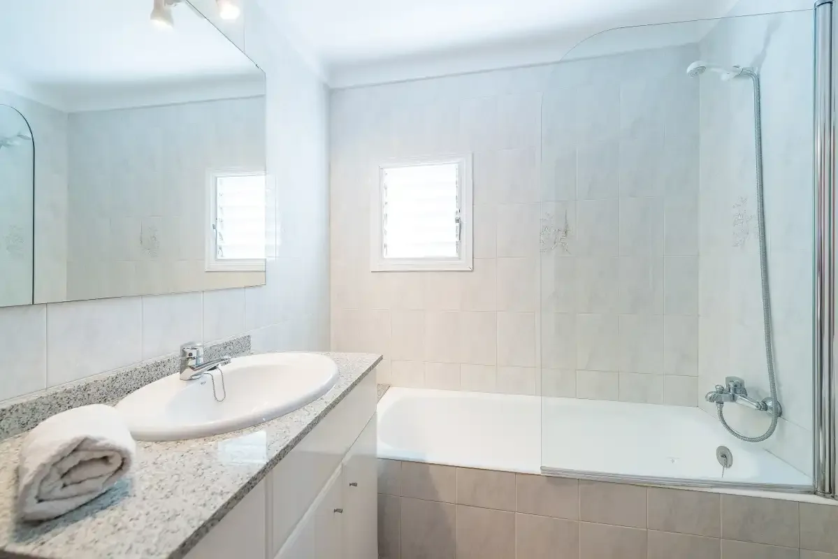 A bright bathroom with a bathtub, shower, and sink.