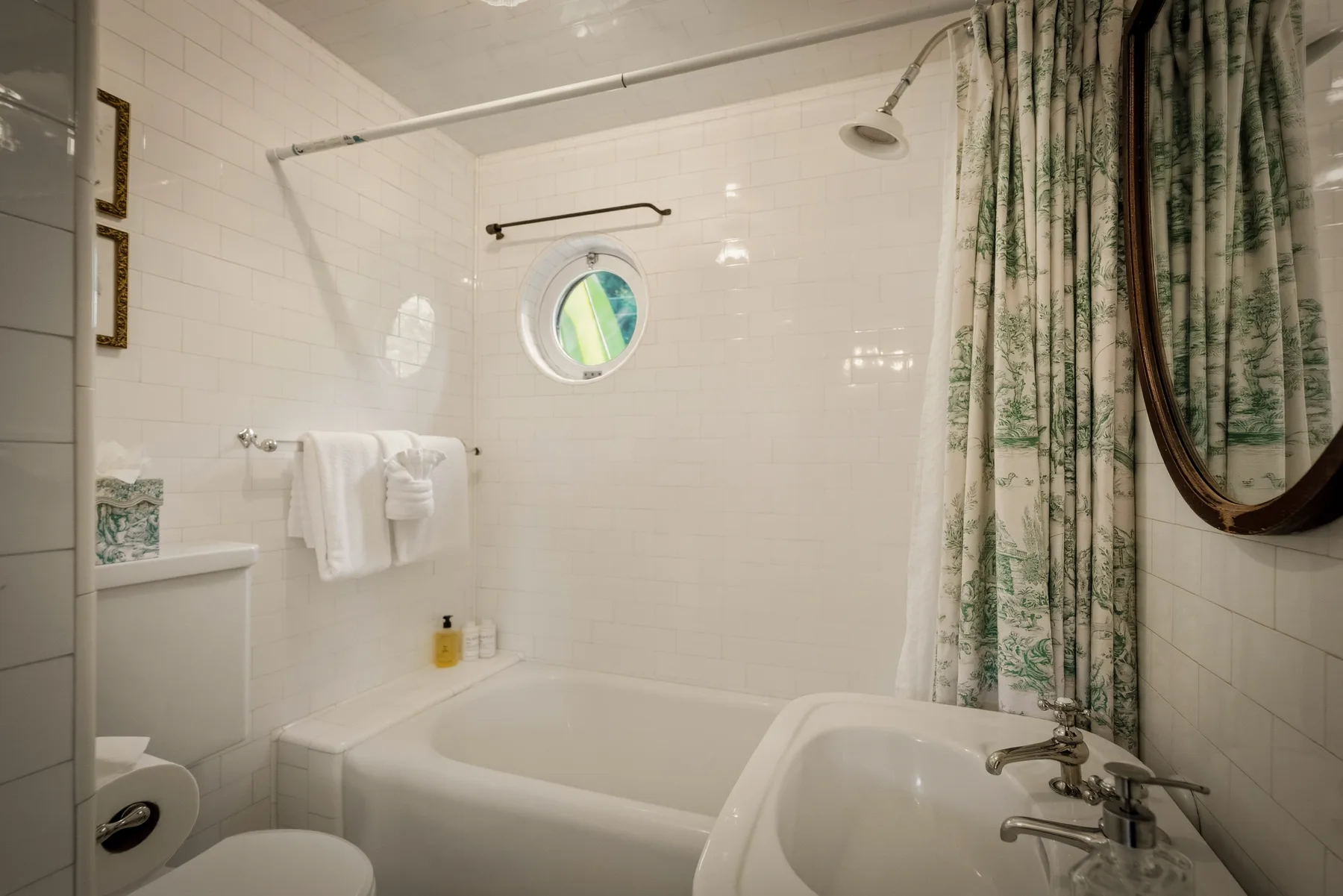 Un baño con azulejos, bañera, ducha y cortina estampada.