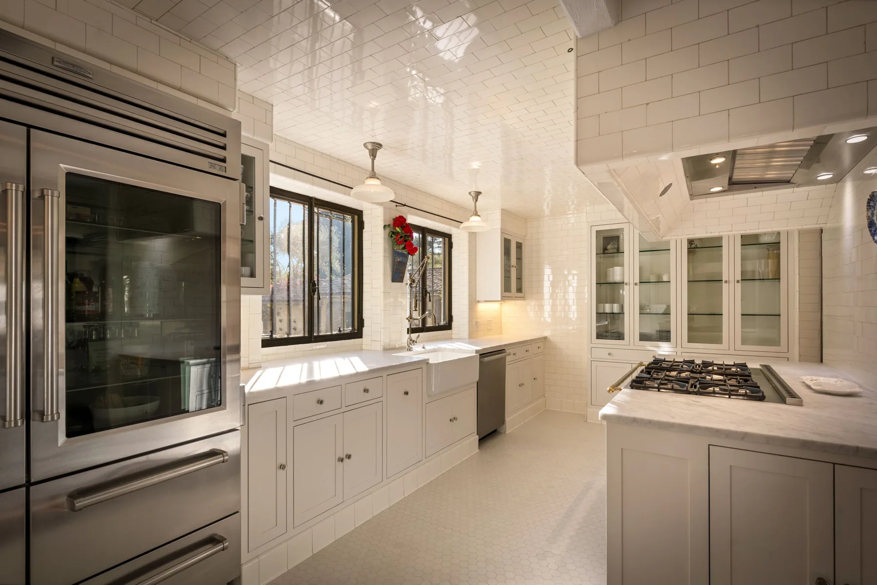 Una cocina luminosa con gabinetes blancos, un horno integrado y una placa de cocina.