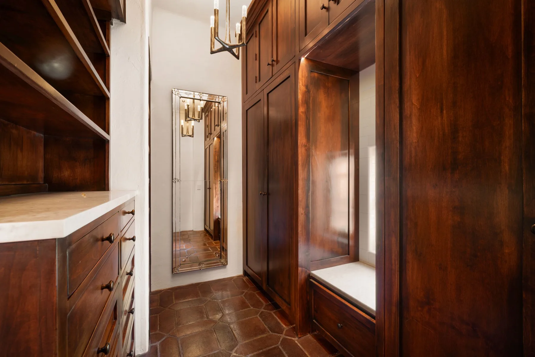 Un vestidor revestido de madera con armarios empotrados y un espejo alto.