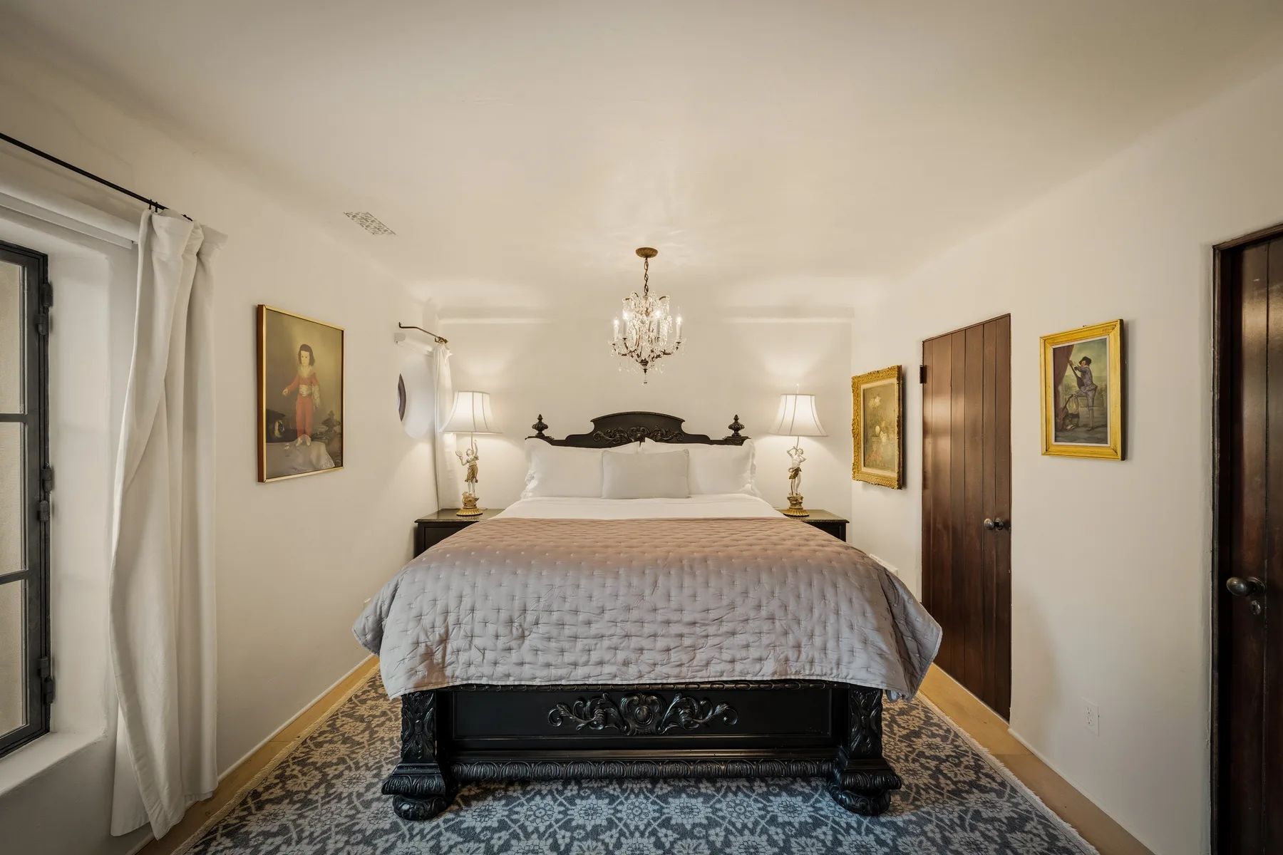 Un dormitorio con una cama grande, mesitas de noche y cuadros enmarcados.