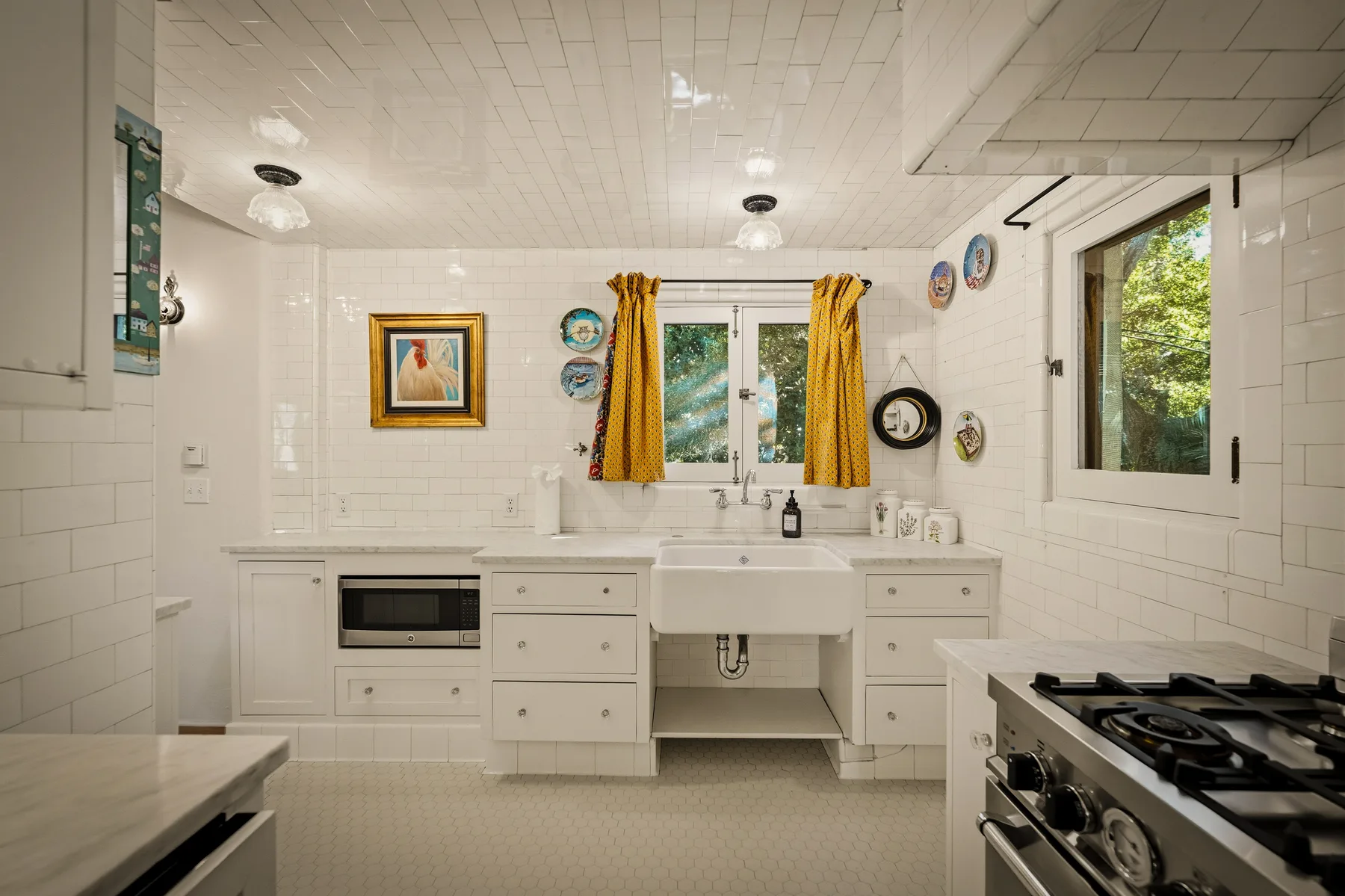 Una cocina luminosa con una encimera blanca, ventanas y una estufa de gas.