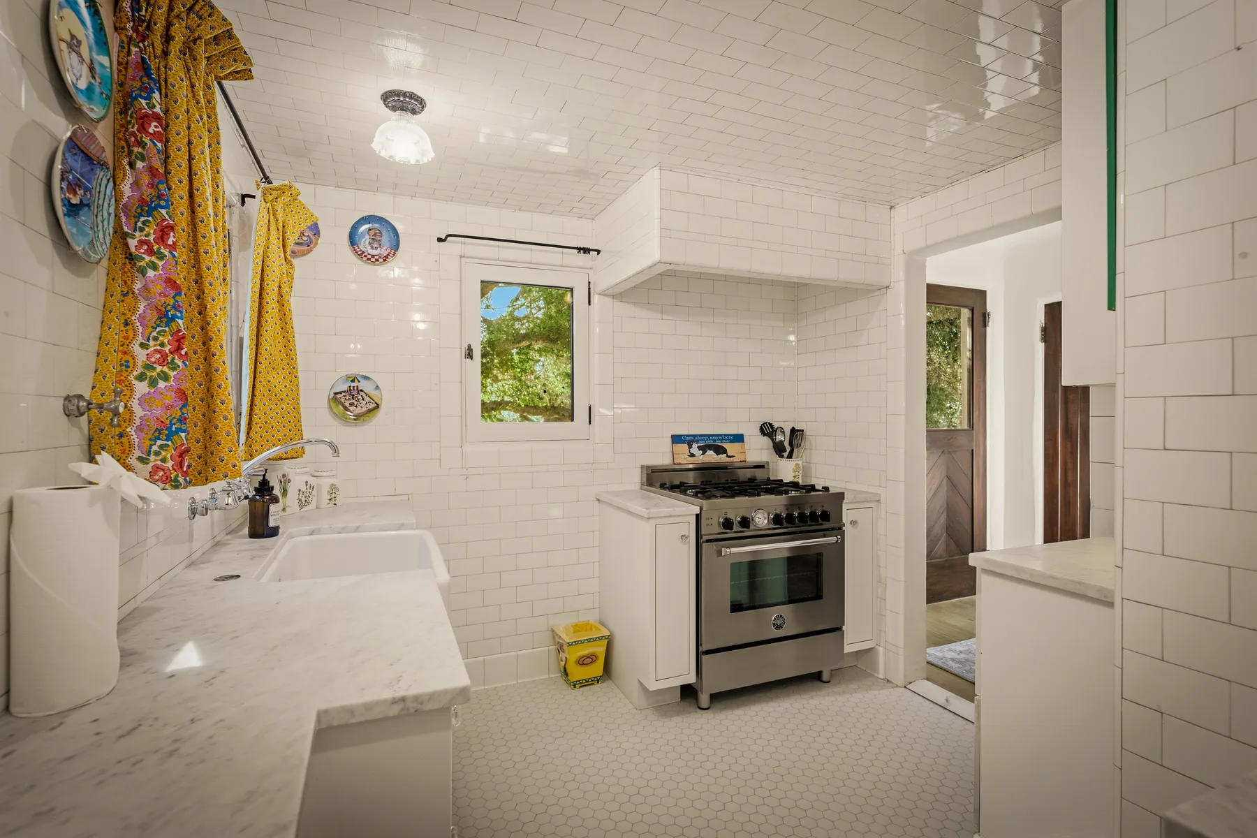 Una cocina luminosa con azulejos, estufa, encimera y una ventana pequeña.