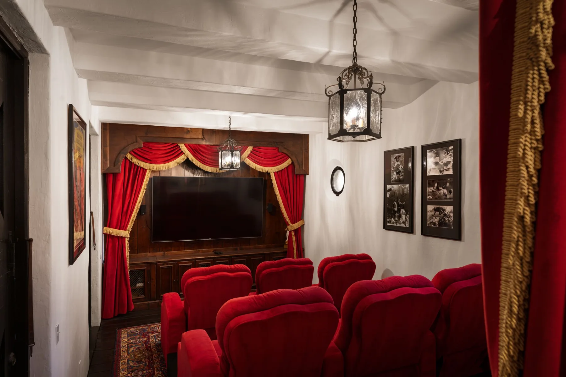 Una pequeña sala de cine en casa con filas de asientos rojos frente a una pantalla grande.
