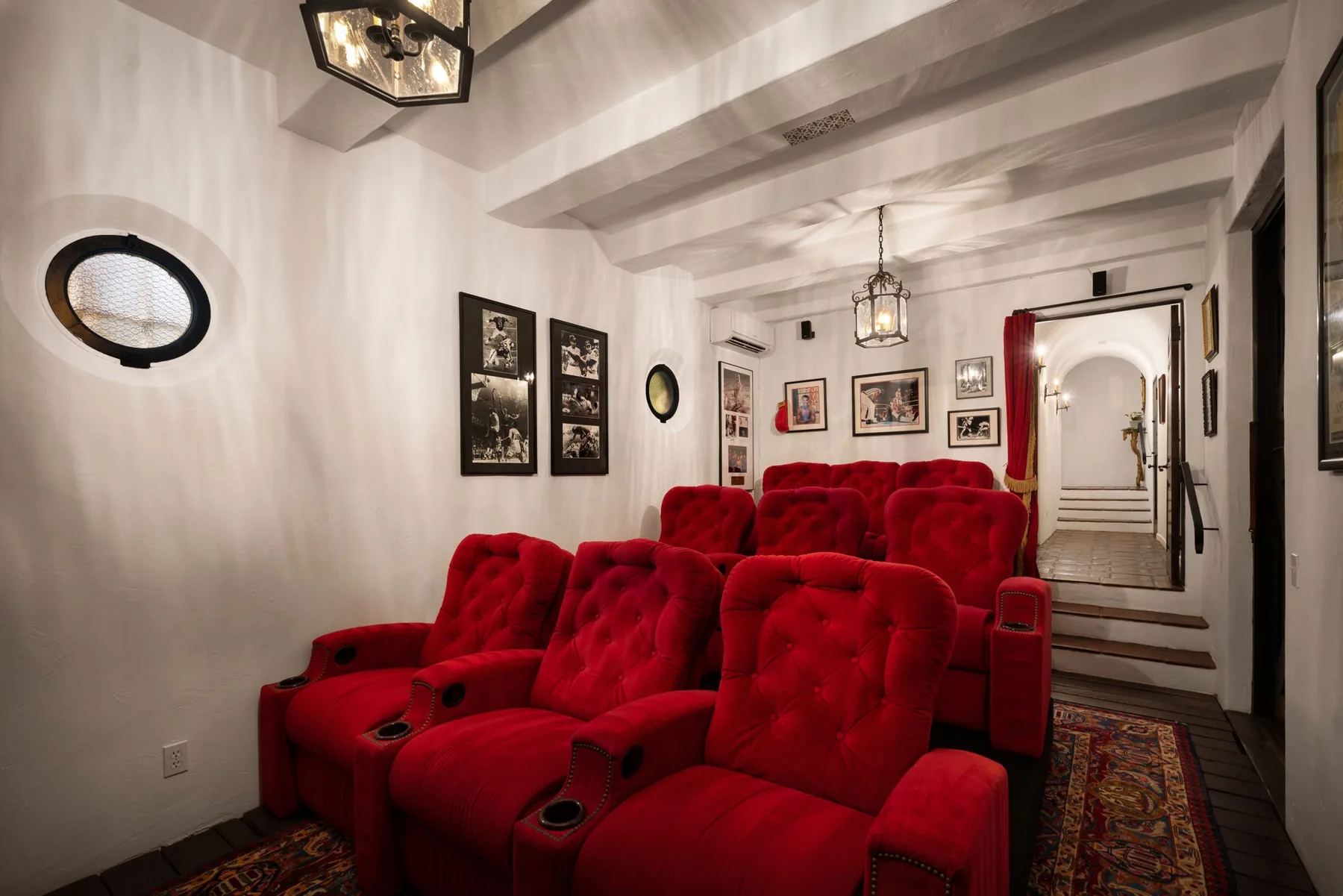 Una sala de cine con filas de asientos rojos y cuadros en las paredes.