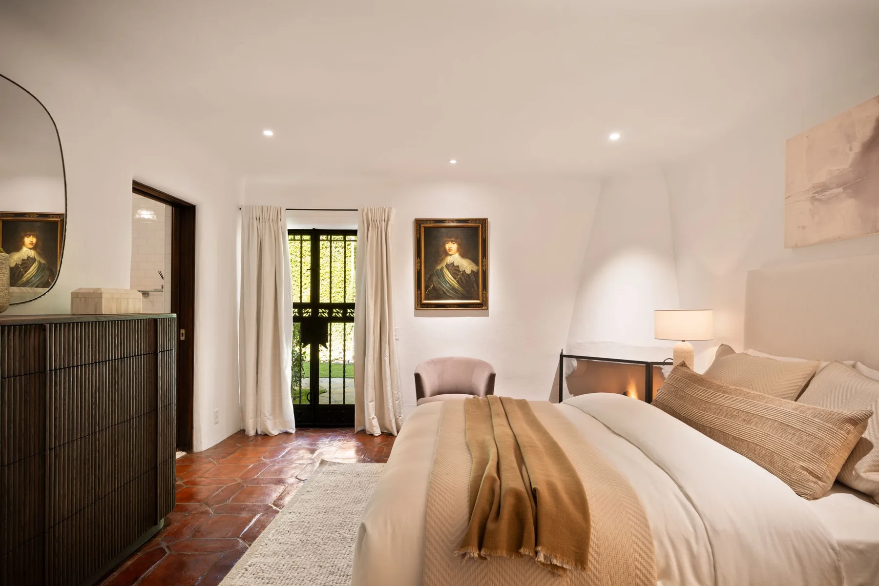 Un dormitorio con una cama grande, una lámpara de noche y puertas de vidrio con cortinas.