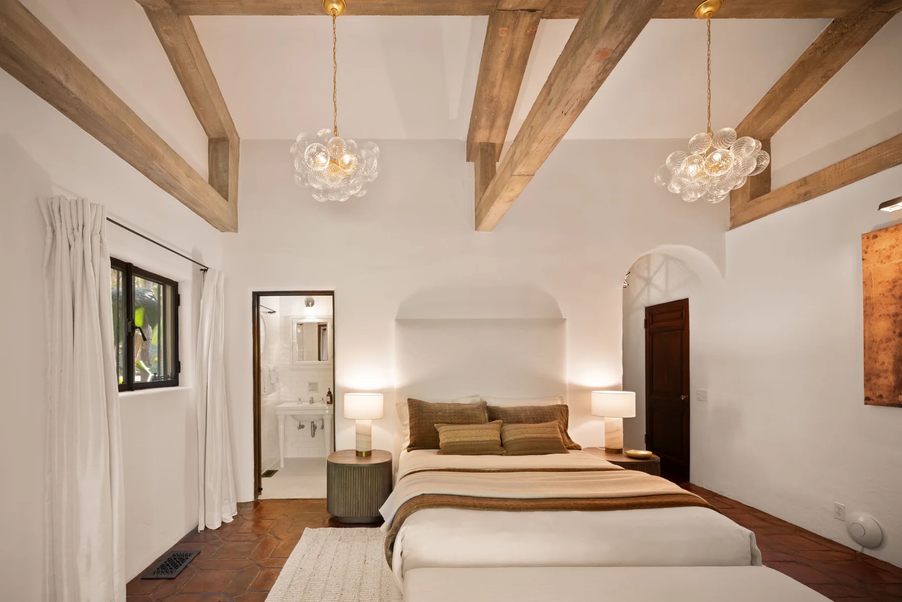 Un dormitorio con una cama grande, vigas de madera vistas y lámparas de noche.