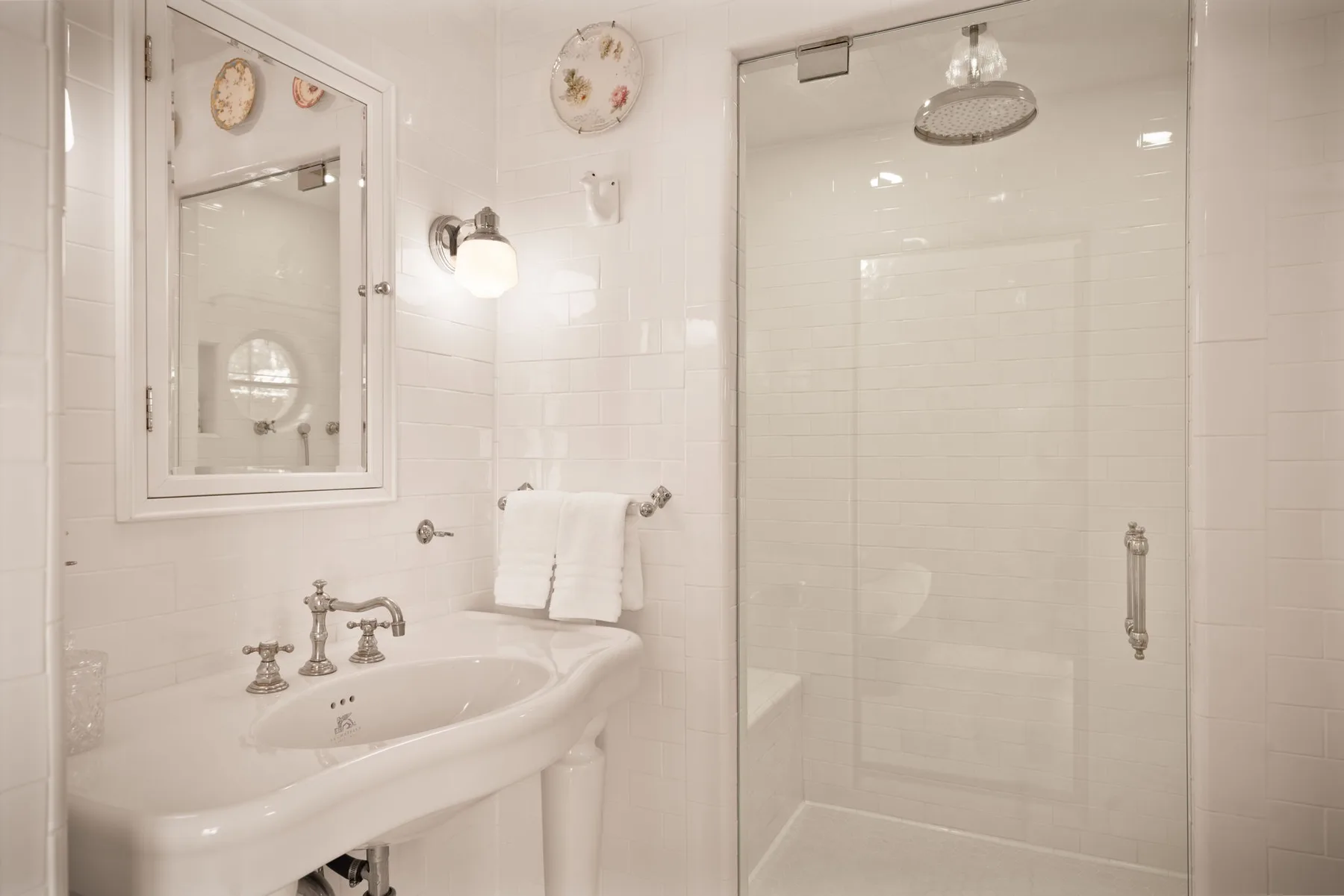 Un baño luminoso con lavabo, espejo y ducha de vidrio.
