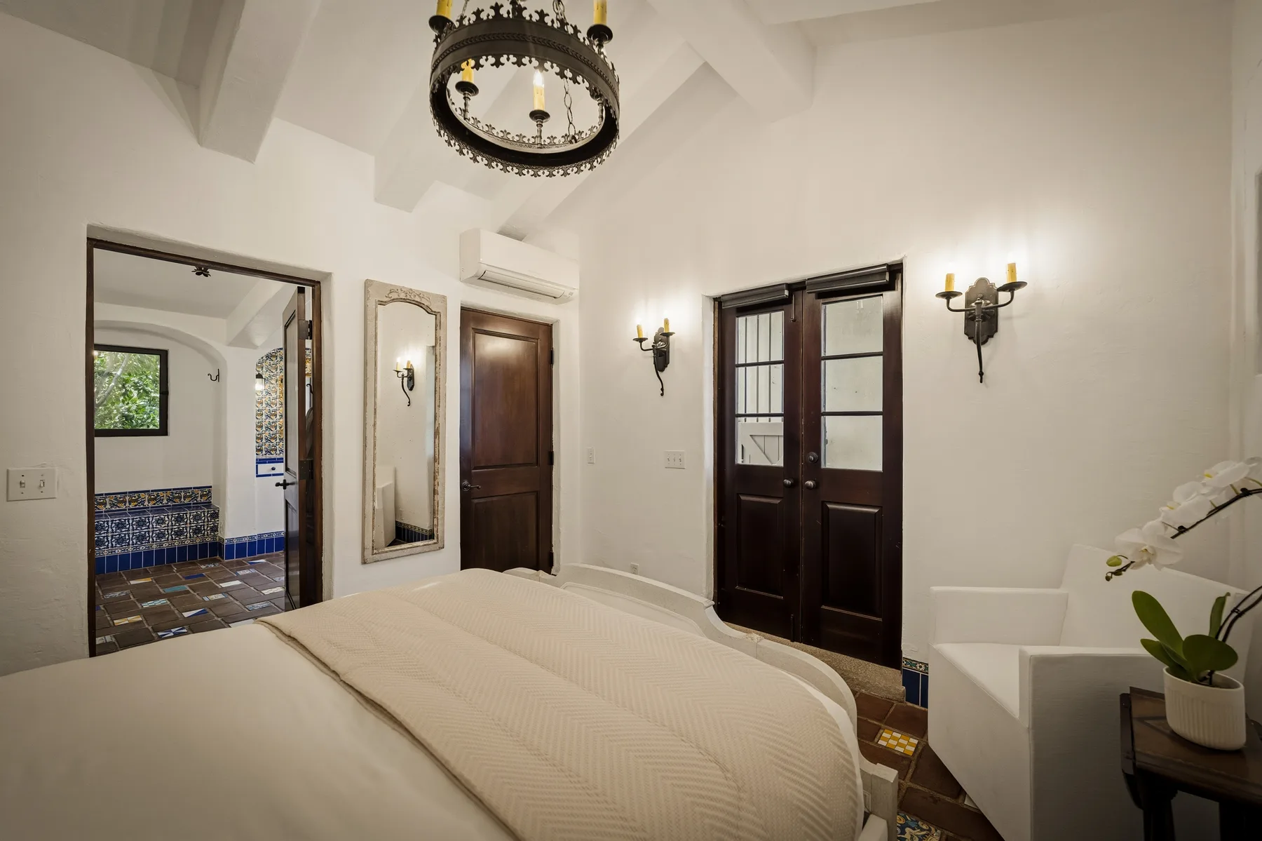 Un dormitorio con una cama grande, puertas de madera oscura y lámparas de pared.