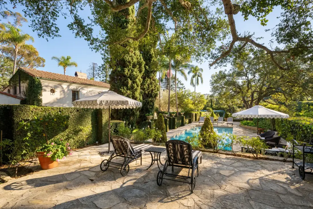 Un patio ajardinado con asientos al aire libre da a una piscina.