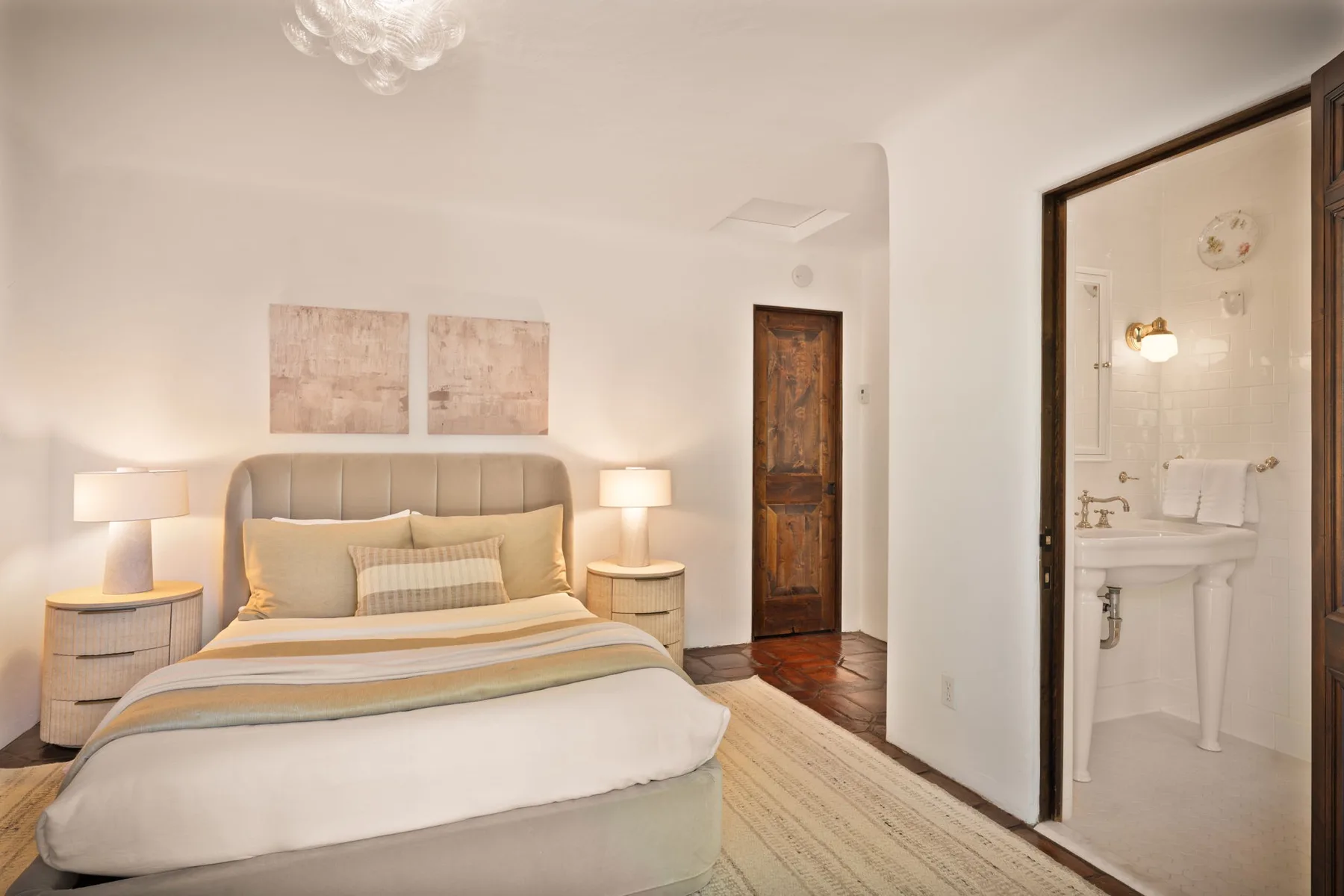Un dormitorio con una cama bien tendida y un baño contiguo.