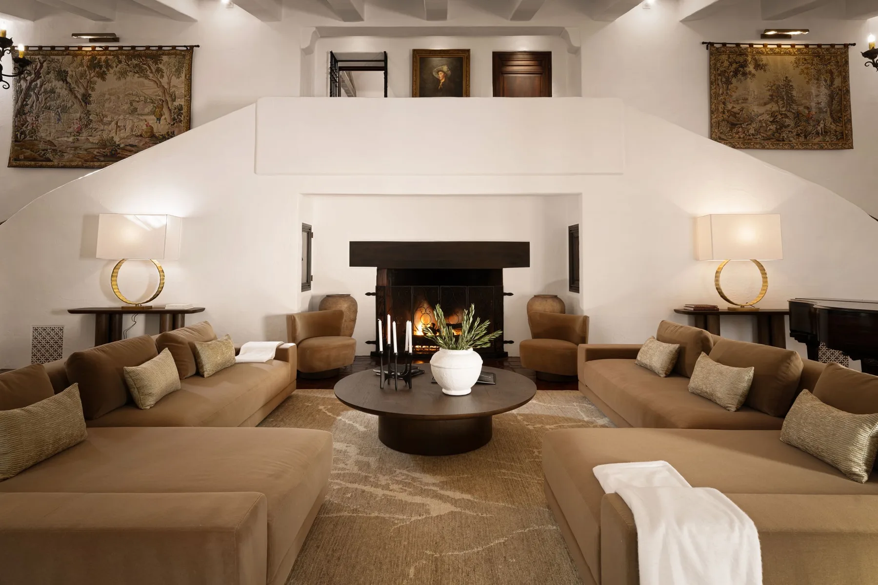 Una sala de estar con asientos color canela alrededor de una chimenea y una mesa de centro.