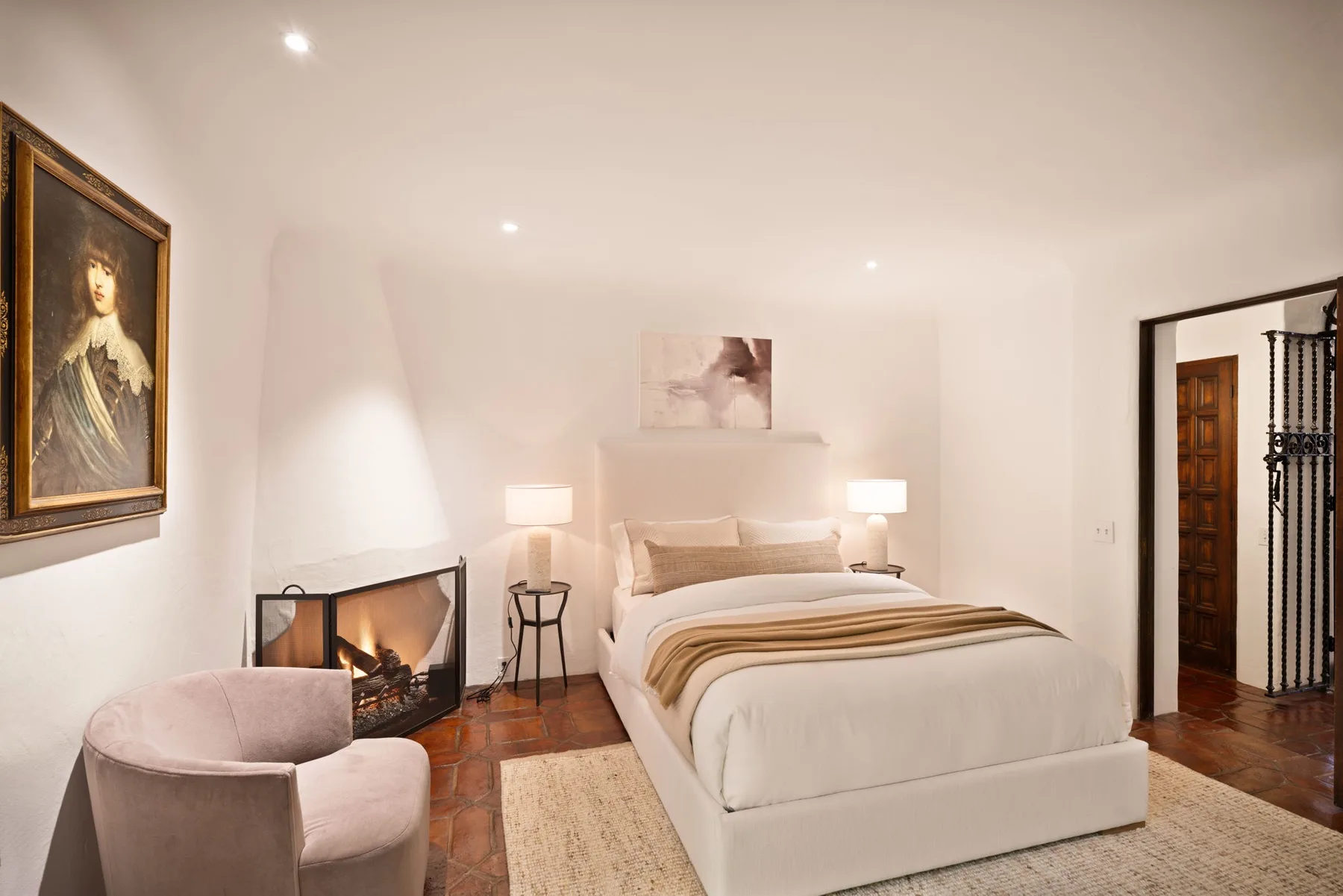 Un dormitorio luminoso con una cama tendida y una chimenea.