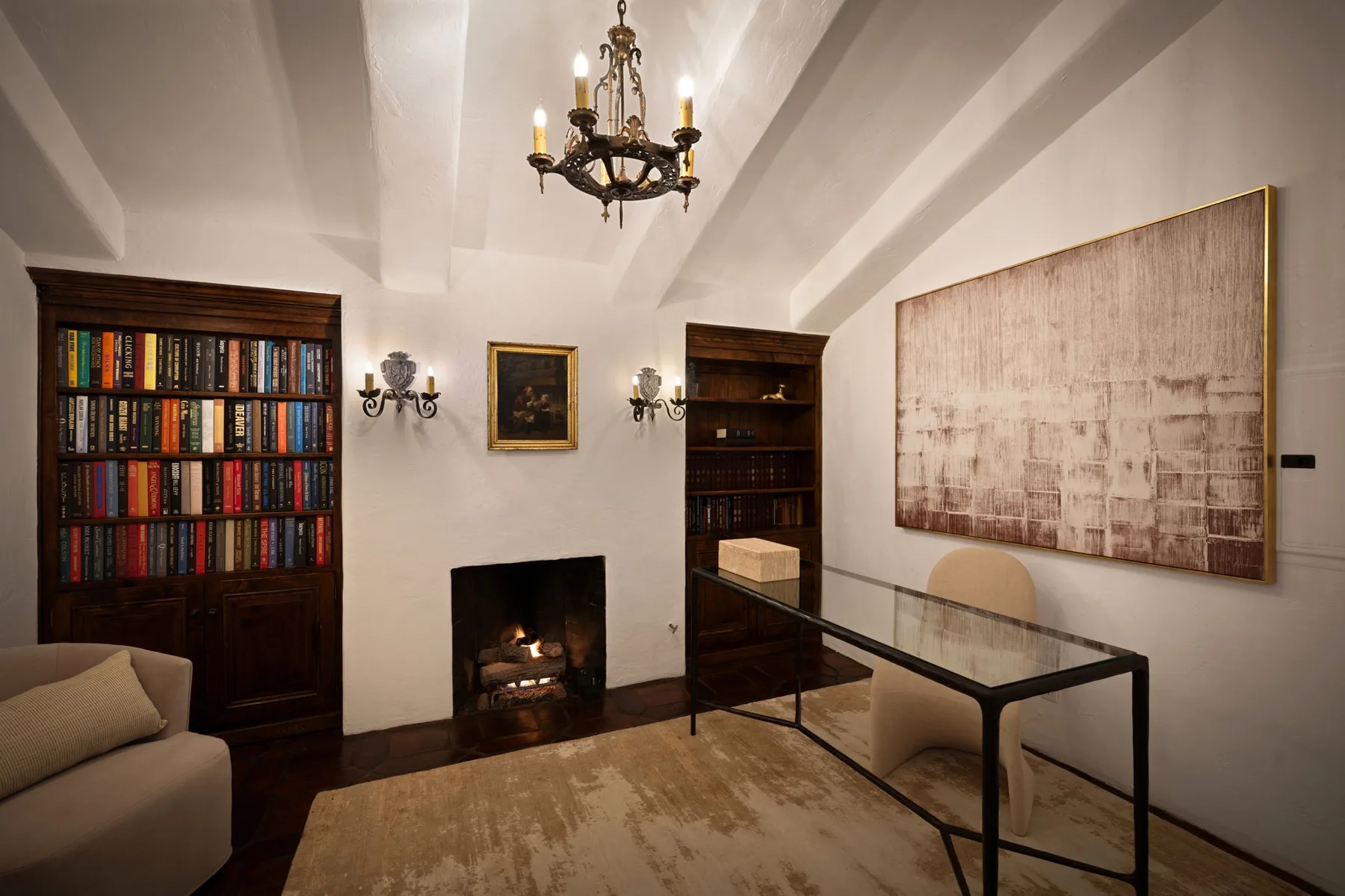 Una sala de estar con chimenea, estanterías y una mesa con superficie de vidrio.