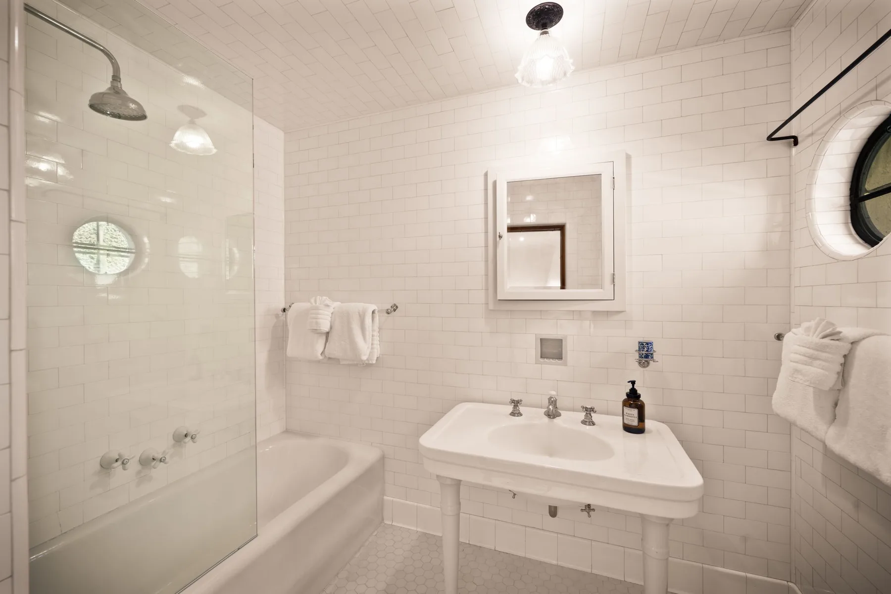 Un baño con azulejos, bañera, lavabo y espejo de pared.
