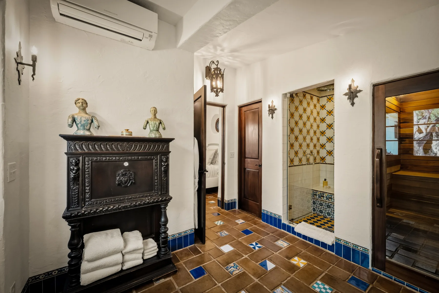 Un pasillo interior con suelo de baldosas, un mueble oscuro y varias puertas.