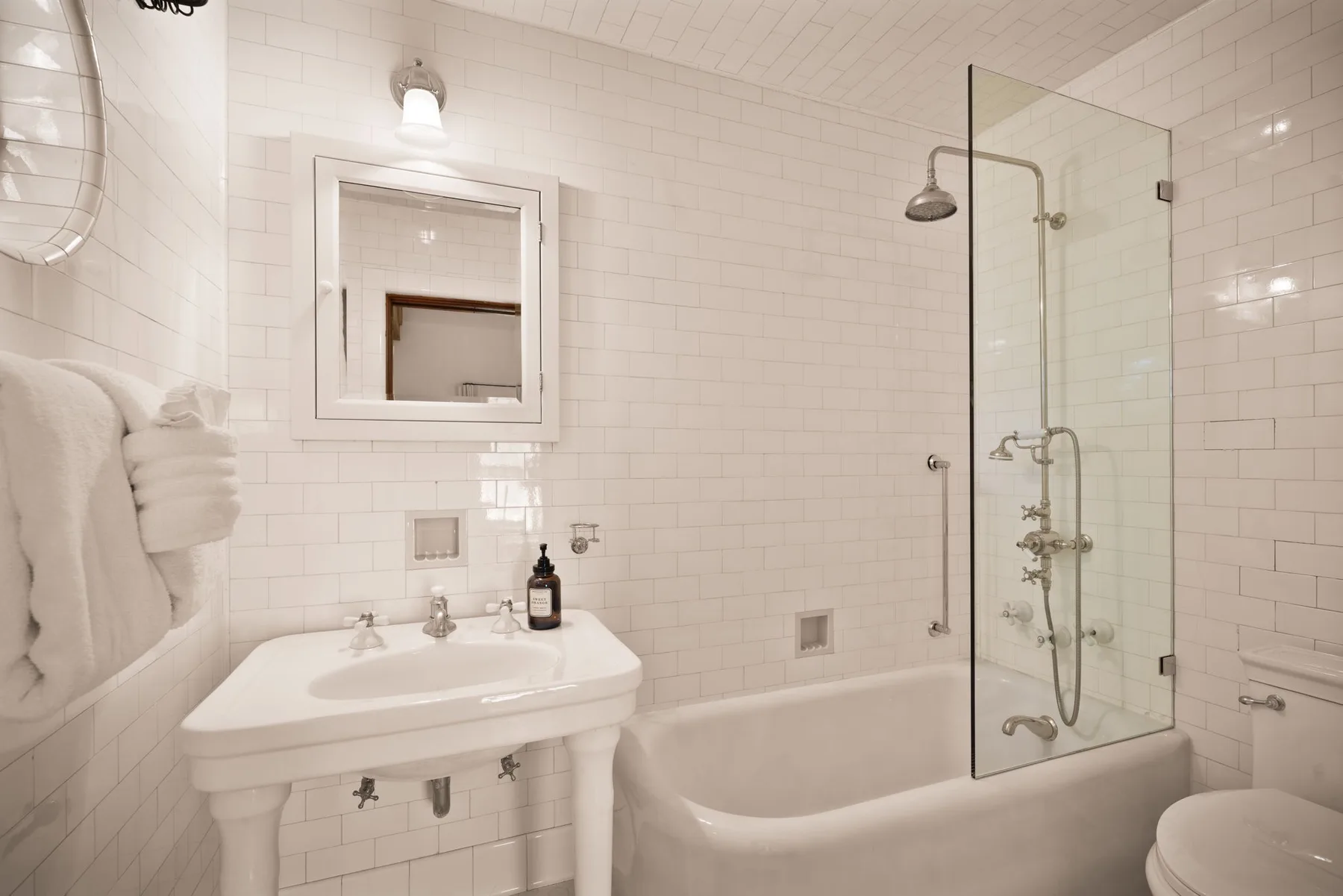 Un baño con azulejos, lavabo, bañera y mampara de ducha de vidrio.